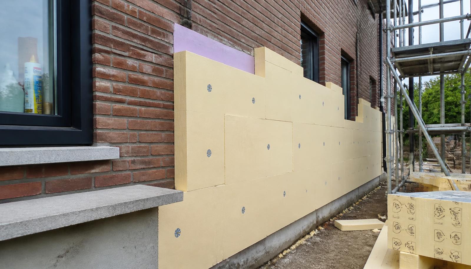 Plaatsing van isolatieplaten op een gevel tijdens bouwwerkzaamheden